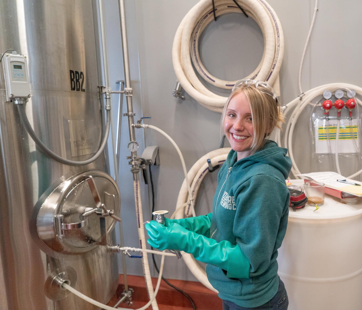 woman wearing pair of teal rubber gloves standing near white barrel